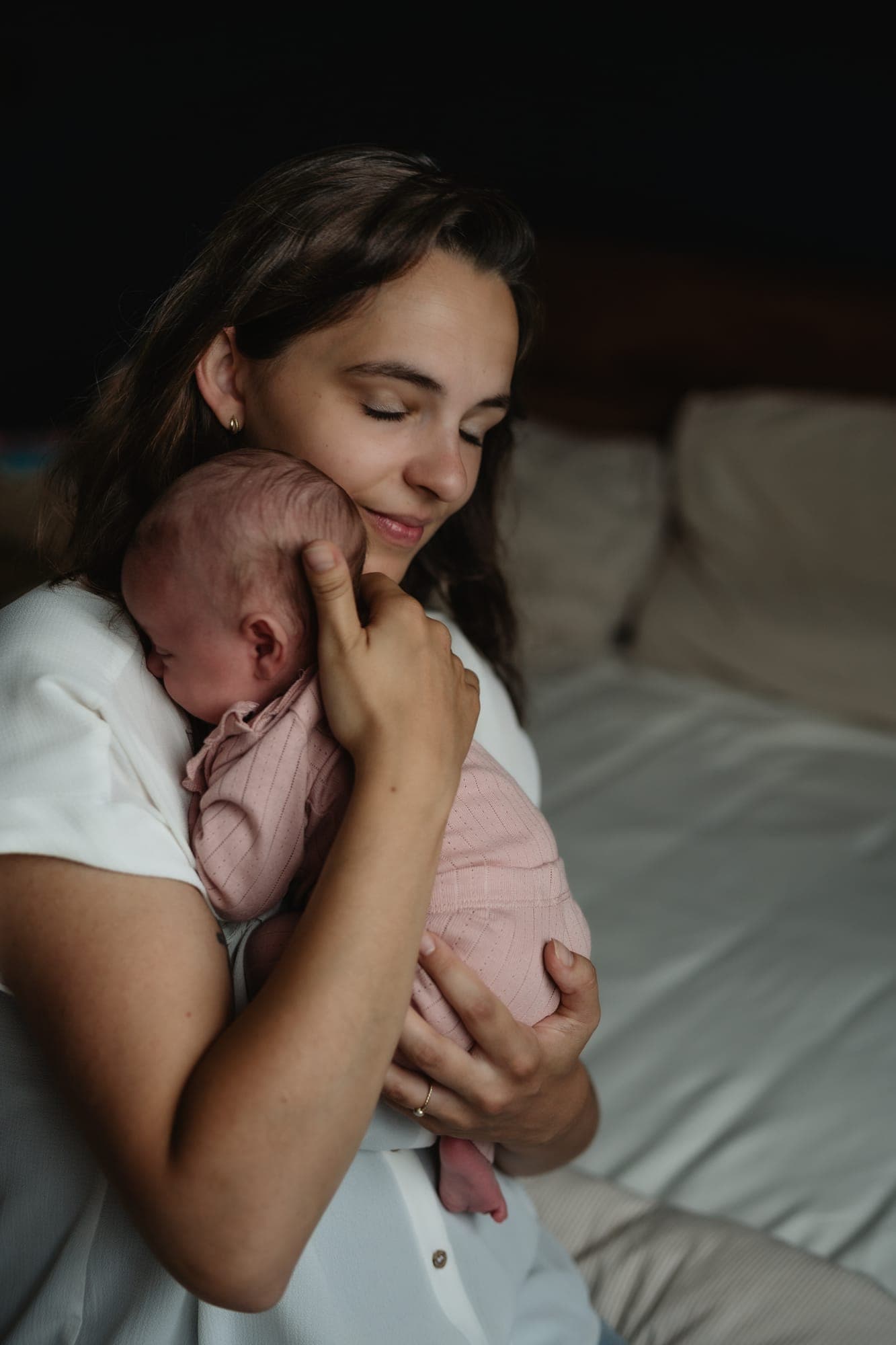 Een moeder houdt haar newborn met gesloten ogen tegen haar wang
