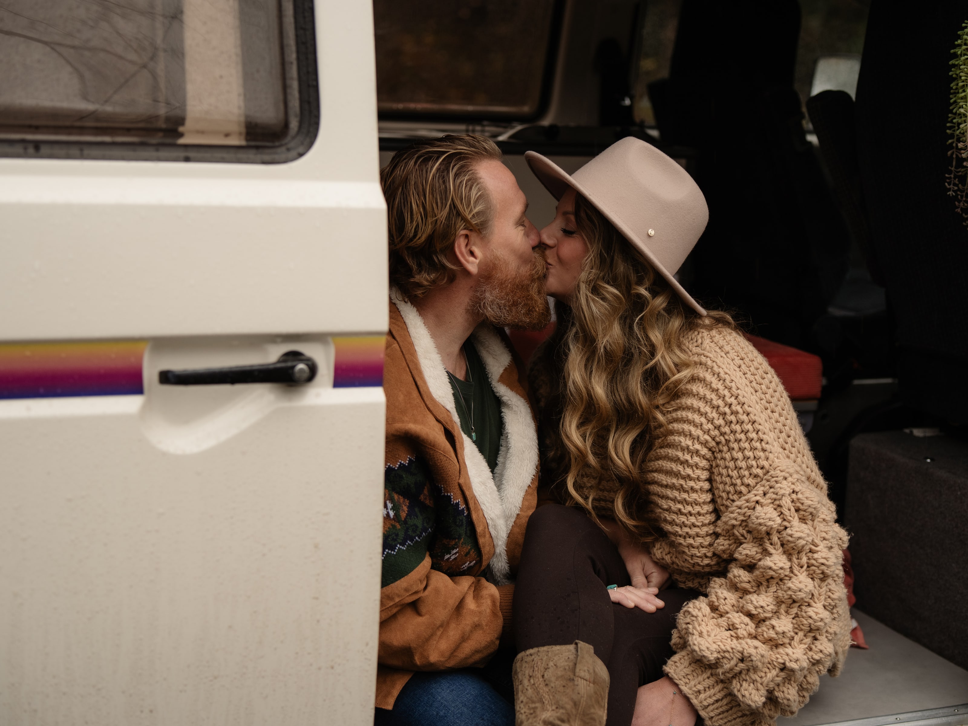 Een stel kust elkaar in de open deur van een oud busje